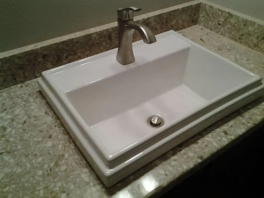 A finished bathroom vanity installation with a brushed nickel faucet set on a granite counter